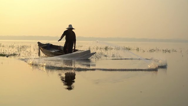 Fishermen on a rowing boat are fishing with a net.