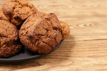 Handmade cookies from oats lie on a black tray on an old wooden table