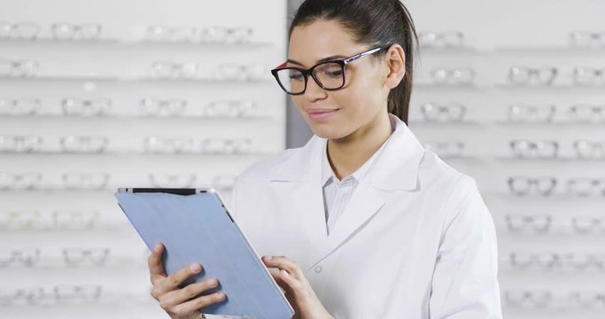 An ophthalmologist while using the ipad, turns around looks at the camera and smiles. Concept of: technology, application for ophthalmologists, medical examinations.