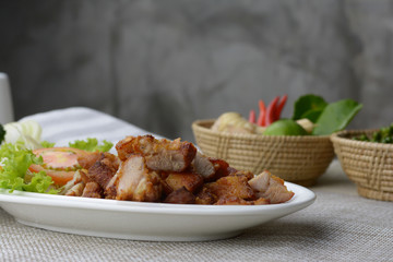 Deep fried pork belly with fish sauce on the table and gray cement background.