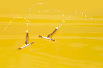 Two intrauterine coils on yellow background