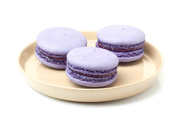 Beige plate with three violet macarons on white