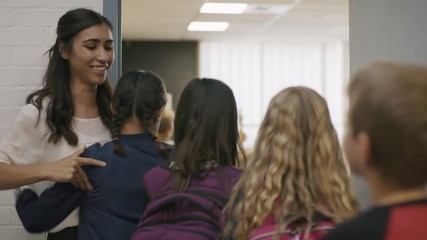 Enthusiastic teacher greeting students entering doorway to classroom / Provo, Utah, United States - Powered by Adobe