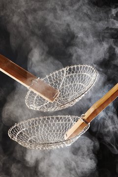 Two empty metal mesh strainers with steam rising