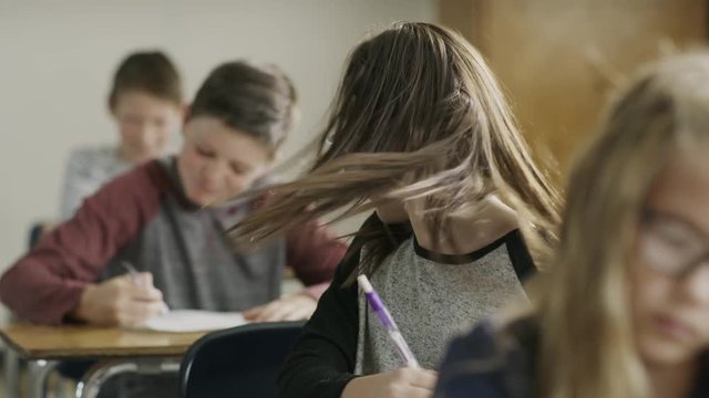 Boy playfully pulling hair of girl studying in classroom / Provo, Utah, United States