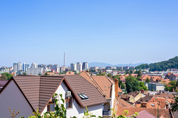 Daylight sunny view to city buildings and green mountains full of trees