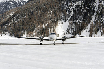  A front view of a private jet ready to take off in the snow covered landscape and mountains in the alps switzerland in winter