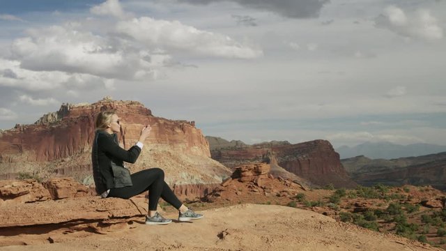 Woman photographing scenic view of desert landscape with cell phone / Capitol Reef National Park, Utah, United States