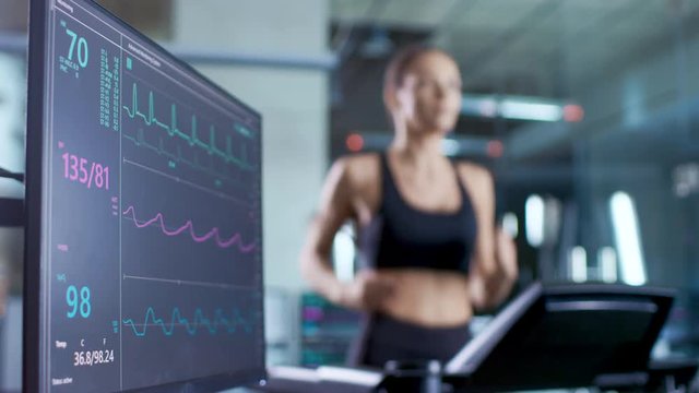 Medical Monitor Shows EKG Reading of a Woman Athlete Running on a Treadmill. Focus on Monitor.