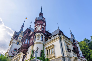 Daylight view from bottom to Peles castle and bright blue sky with clouds