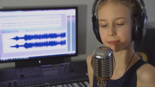 Little girl recording a song in home recording studio.