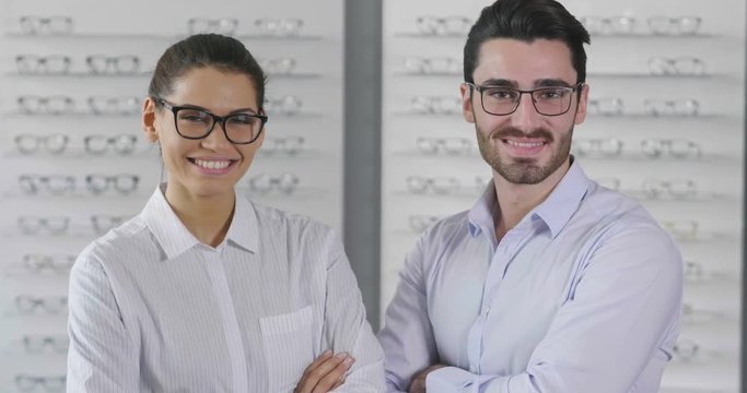 Portrait of two ophthalmologist doing a visual examination for a customer at an optical center. Try the spectacles to the patient. Concept of: medical examination, assistance, optics and customer care