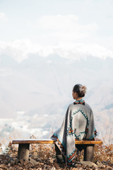 Woman resting on a bench in front of mountains.