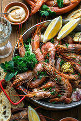 Roasted prawns shrimps in a pan with lemons, bread and wive