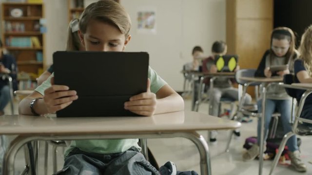 Panning shot of children in classroom reading digital tablets / Provo, Utah, United States