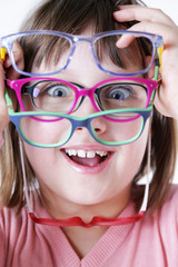 Dziewczynka trzyma kolorowe oprawki okularów.