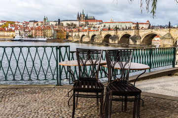 Panorama with Table and chairs of cafe on background Prague castle and river Vltava, Czech Republic