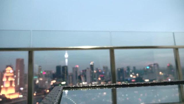 Happy woman drinking a glass of white wine while sitting in rooft bar in the city or on the terrace with cityscape at sunset. Vacation,happiness,freedom concept.