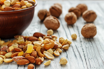 Mix nuts in earthenware on a wooden background.