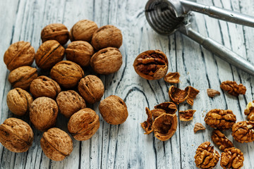 Whole walnuts on a white wooden background with nectic cutters.
