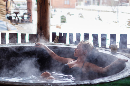 Young woman in an open air bath while snowing