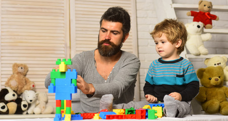Dad and kid with toys on background build of blocks