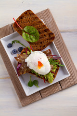 Poached egg, bacon, smashed white bean and avocado on toast. Sandwich. View from above, top, vertical