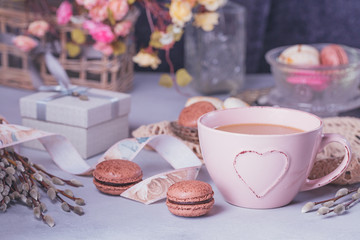 Pink coffee mug with sweet pastel french macaroons, gift box and pussy willow