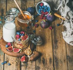 Healthy vegan breakfast. Oatmeal granola with bottled almond milk, honey, fresh fruit and berries on hoard over rustic wooden table background, copy space. Clean eating, weight loss food concept