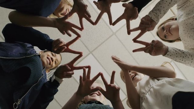 Low angle view of smiling girls joining fingers in unity / Provo, Utah, United States