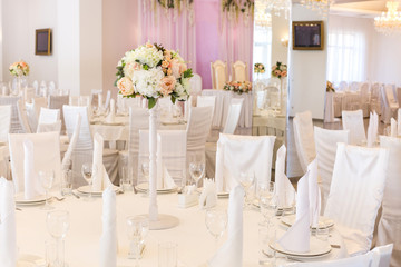 interior, furniture, engagement concept. there is a place decorated with bouquet of flowers and lots of white colour, everything, tables and chaires covered with white textile