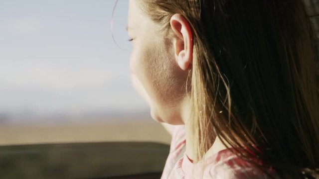 Close up of girl in car with arm outstretched enjoying wind / Hanksville, Utah, United States