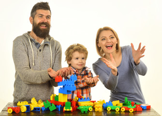 Family with cheerful faces build cars of colored construction blocks