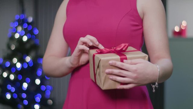 Closeup of a woman's hands holding and fumbling a Christmas gift or present. A happy wife concept. Soft focus