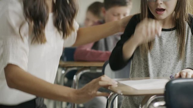 Pan up to teacher assisting girl with assignment in classroom / Provo, Utah, United States