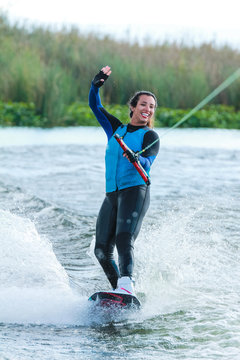 Mixed race fit young woman wakesurfing on a lake in California on a clear summer day
