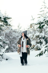 A beautiful girl walks through the snowy winter coniferous forest.