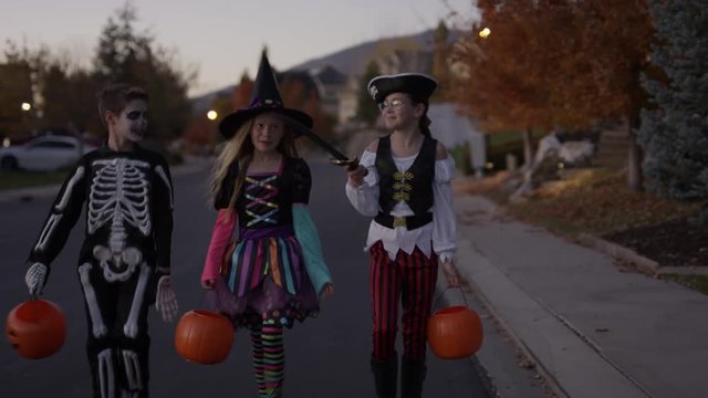 Front view tracking shot of children walking in neighborhood on Halloween / Cedar Hills, Utah, United States