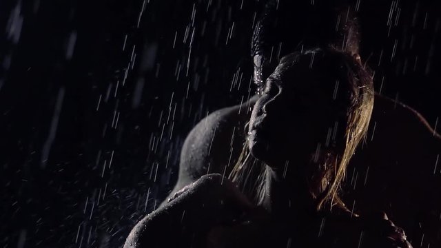 lovers are embracing under water flows in darkness, man is touching woman tenderly from back