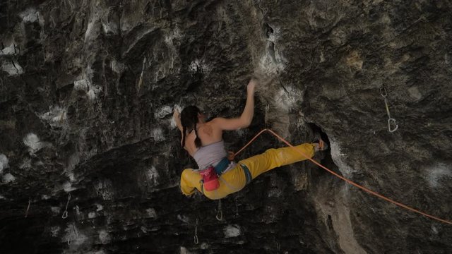 Woman rock climbing sideways in cave / American Fork Canyon, Utah, United States