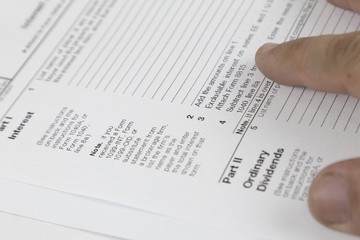 Obraz premium Tax concept. Man looking through US tax form with hands