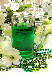 Mug filled with green beverage with gladiolas and green beads surrounding it.  Ideal for St. Patrick's day.
