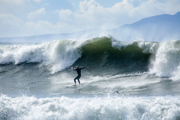 Surfer in California surfs large wave in beautiful blue water at beach