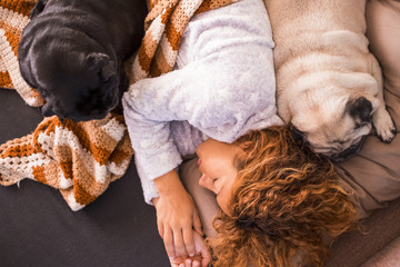 a beautiful woman sleep with her two dog pugs on the sofa at home. Sunday morning and protection concept.