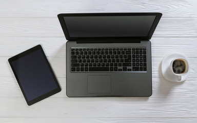 Laptop and coffee cup on white wooden desktop