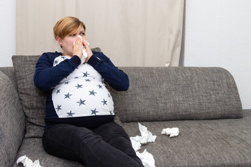 Schwangere Frau ist erkältet und putzt sich die Nase - 192381359