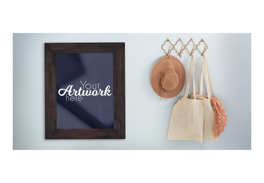 Picture Frame Mockup on Blue Wall with Hanging Hat and Bags