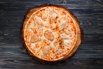 Traditional italian food. Fresh pizza with chicken and pineapple on rustic wooden background flat lay. Restaurant menu photo.