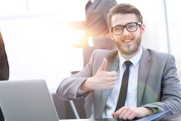 Manager sitting at his Desk and showing thumbs up