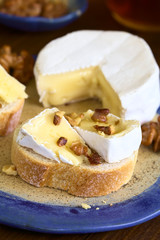 Baguette with camembert cheese and walnuts, photographed with natural light (Selective Focus, Focus on the first walnut pieces on the bread)